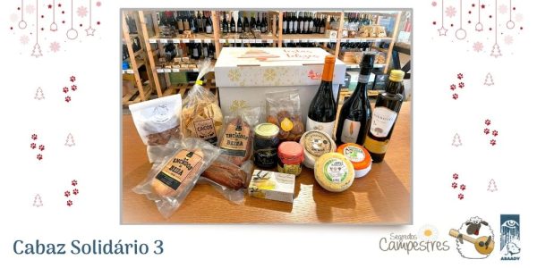 Uma fotografias onde estão vários produtos regionais (uma garrafa de espumante, uma de vinho e uma de azeite, vários enchidos, bolos, 3 queijos, doce de abóbora, um enlatado, uma embalagem de nozes e um frasco de mel) em cima de um balcão. Atrás dos produtos está uma caixa de cartão decorada com estrelas amarelas e árvores de Natal vermelhas e tem a frase “Festas Felizes”. Ao fundo, na fotografia veem-se vários expositores onde se veem garrafas de rótulos diferentes, embalagens de produtos variados. À volta das fotografias estão vários desenhos natalícios a vermelho (pendentes, árvores de Natal, estrelinhas e patitas) Frase a Azul: Cabaz 3